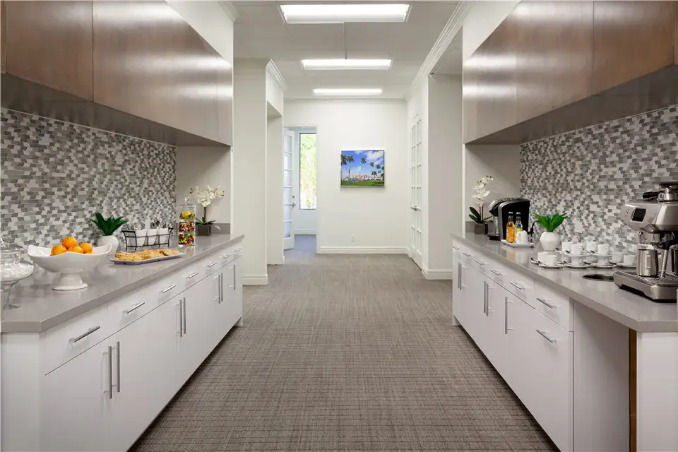 Modern kitchenette with white cabinets, mosaic backsplash, and coffee station at The Suites at 231.
