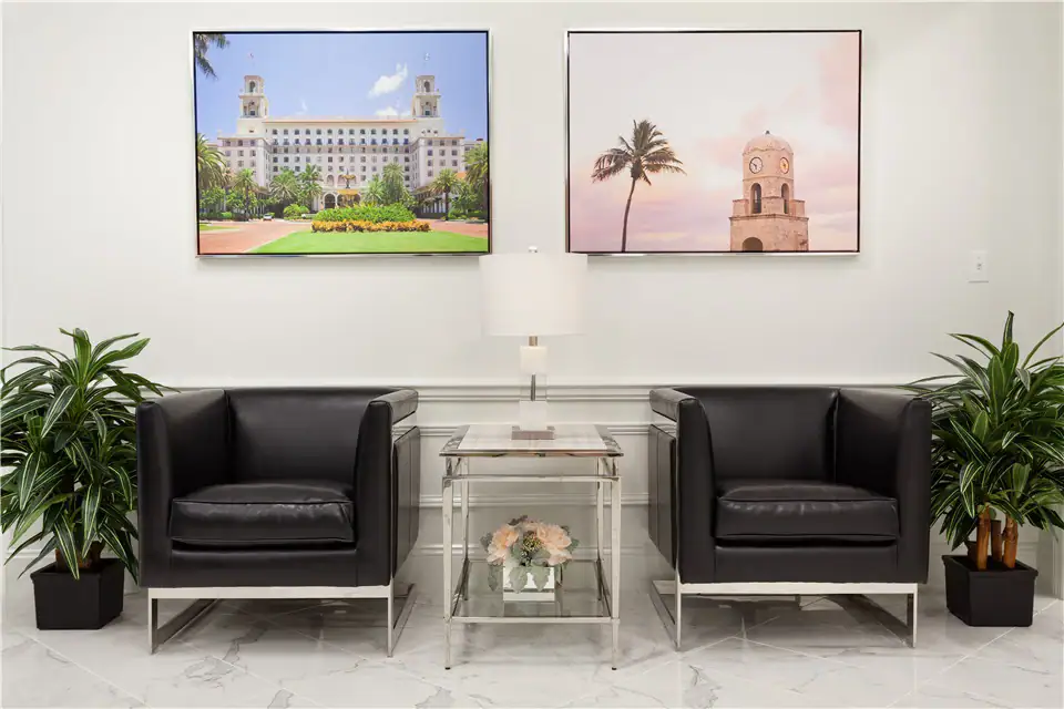 The reception area of The Suites at 231, featuring two leather chairs with a table and a lamp in between them.