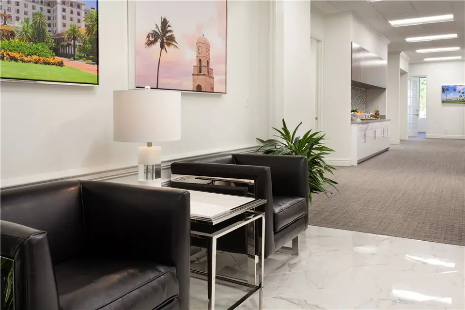 The reception area of The Suites at 231, featuring two leather chairs with a table and a lamp in between them.